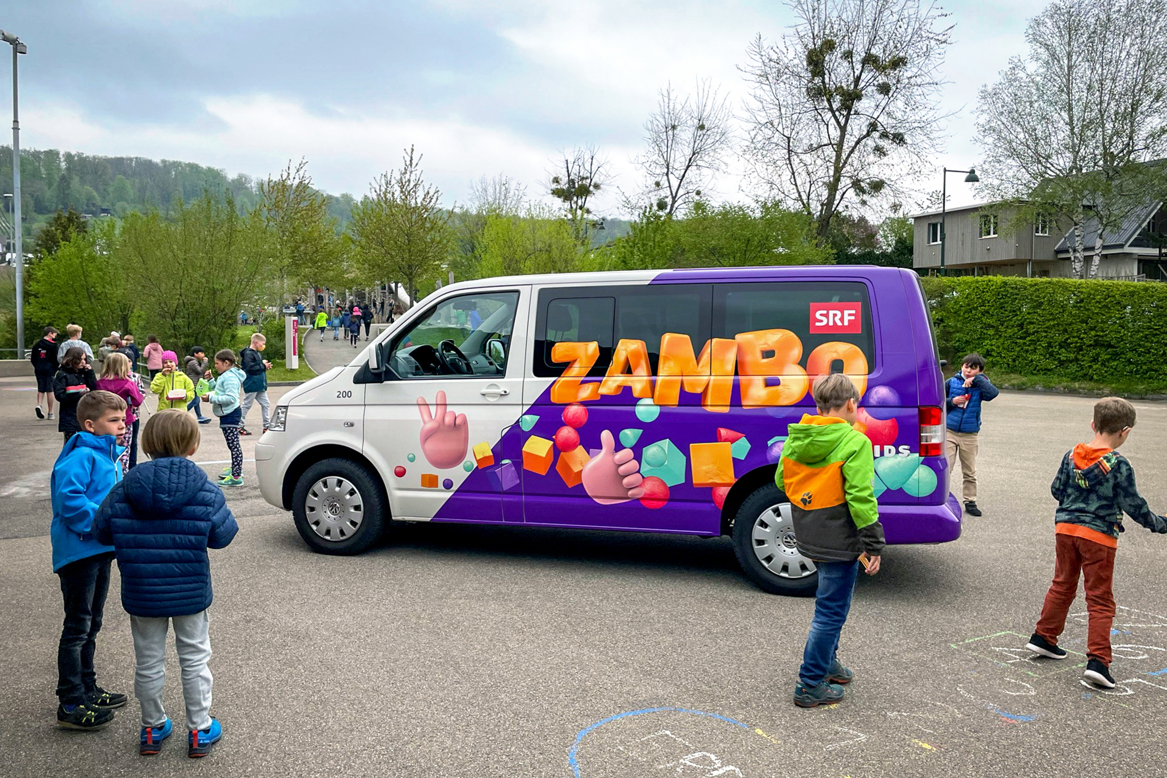 Zambo goht i d’Schuel: SRF Kids bringt das Mikrofon an Schulen  Der «Zambo»-Bus besucht Schulklassen in der ganzen Deutschschweiz. Hier auf dem Pausenplatz des Schulhauses in Biel-Benken. 2021