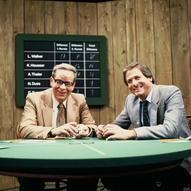 Samschtig-JassModerator Jürg Randegger (re.) und Schiedsrichter Göpf Egg im Samschtig-Jass, Punktetafel im Hintergrund, 1975Copyright: SRF