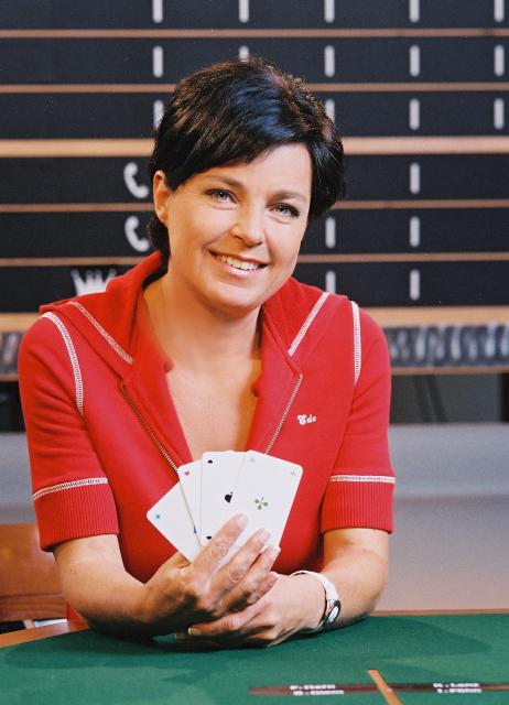 Samschtig-JassModeratorin Monika Fasnacht vor Wandtafel, mit Jasskarten in der Hand