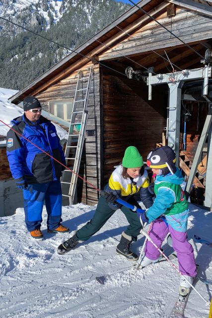 Mona mittendrinIm gefährdeten SkigebietAnstrengender als gedacht: Skiliftmitarbeiterin Mona Vetsch (M.) wird von Routinier Alex Erb beobachtet.2023Copyright: SRF
