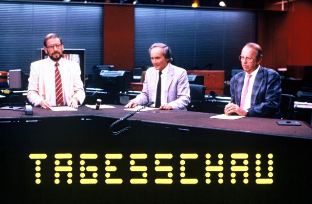 Chronik50 Jahre SF DRSTagesschau Dreiermoderation. v.l. Pierre Freimüller (Redaktor), Léon Huber (Sprecher), Max Wolf (Sport). Tagesschau-Studio im Redaktionsraum. Tagesschau-Signet vorne. 1986Copyright SF DRS
